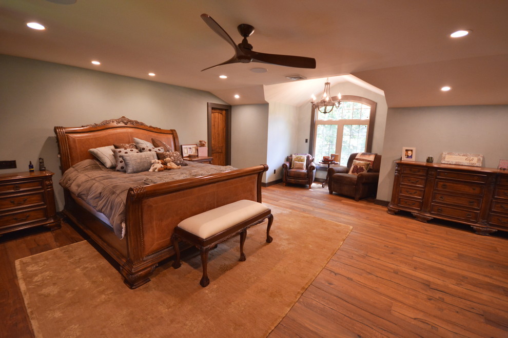 Ejemplo de dormitorio principal rústico grande sin chimenea con paredes azules, suelo de madera en tonos medios y suelo marrón