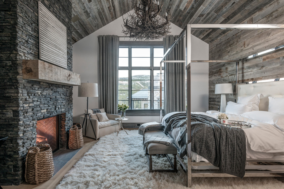 Rustikales Hauptschlafzimmer mit grauer Wandfarbe, hellem Holzboden, Kamin, Kaminumrandung aus Stein und beigem Boden in San Diego
