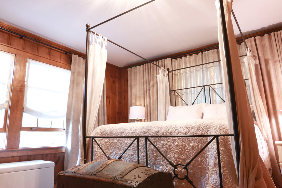 Modelo de dormitorio principal campestre de tamaño medio sin chimenea con paredes marrones, suelo de madera en tonos medios y suelo marrón