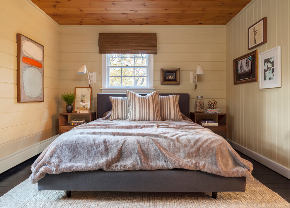 Uriges Schlafzimmer mit beiger Wandfarbe, gebeiztem Holzboden und grauem Boden in New York
