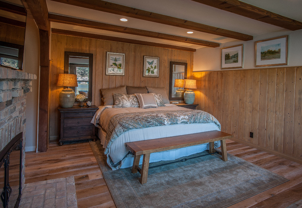Ejemplo de dormitorio principal rústico grande con paredes multicolor, suelo de madera clara, todas las chimeneas y marco de chimenea de ladrillo