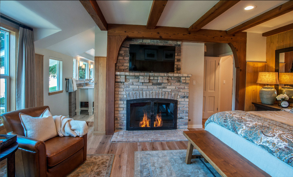 Aménagement d'une grande chambre parentale classique avec un mur multicolore, parquet clair, une cheminée standard et un manteau de cheminée en brique.