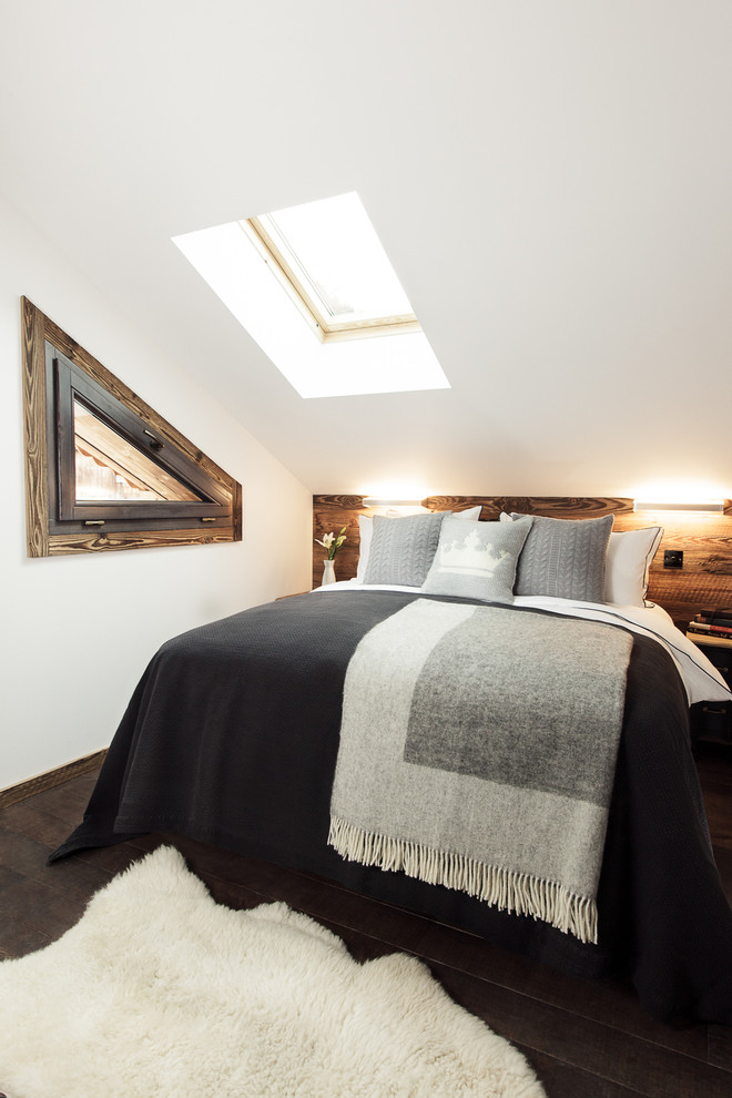 Modelo de dormitorio rústico de tamaño medio con paredes blancas y suelo de madera oscura
