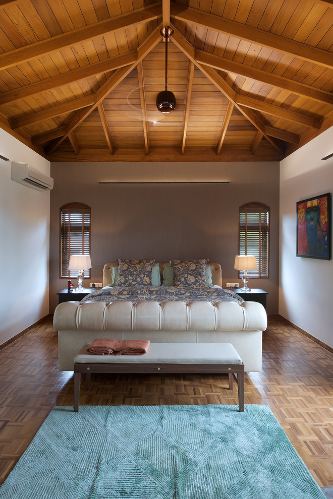 Cette image montre une grande chambre design avec un mur blanc et un sol en bois brun.