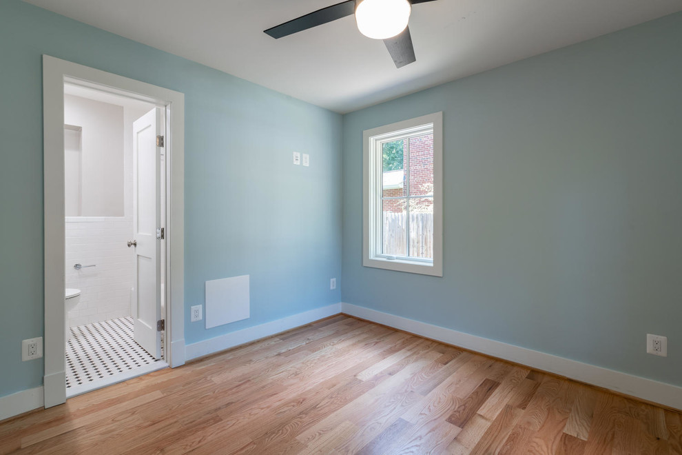 Cette image montre une chambre de taille moyenne avec un mur bleu, un sol en bois brun et un sol marron.