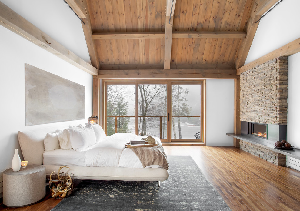モントリオールにある巨大なコンテンポラリースタイルのおしゃれな主寝室 (白い壁、無垢フローリング、標準型暖炉、金属の暖炉まわり、ベッド下のラグ)