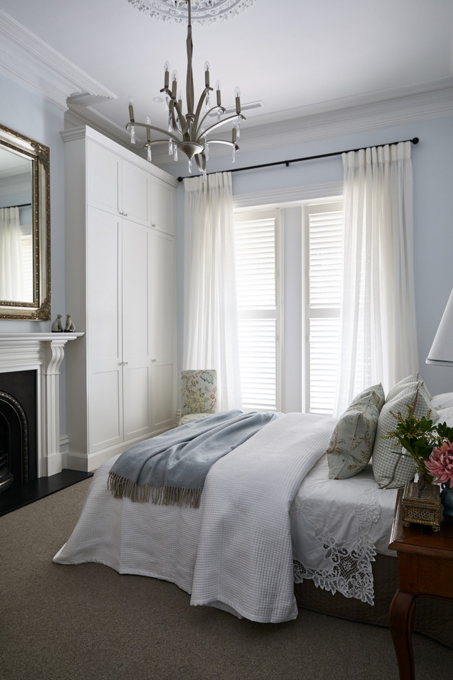 Стильный дизайн: гостевая спальня (комната для гостей) в классическом стиле с синими стенами, ковровым покрытием, стандартным камином, серым полом и тюлем - последний тренд