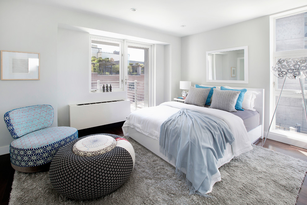 Example of a large trendy loft-style medium tone wood floor bedroom design in New York with white walls and no fireplace