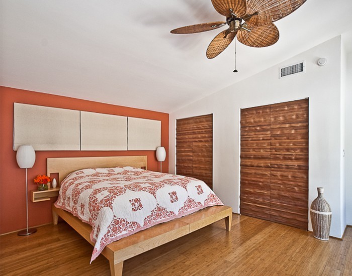 Photo of a retro master bedroom in Los Angeles with orange walls and light hardwood flooring.