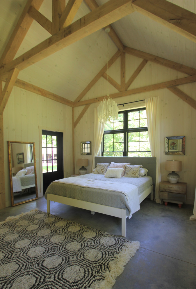 На фото: гостевая спальня среднего размера, (комната для гостей) в стиле кантри с балками на потолке, сводчатым потолком, бежевыми стенами, бетонным полом, серым полом и деревянными стенами