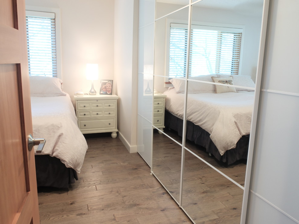 エドモントンにある中くらいなトランジショナルスタイルのおしゃれな客用寝室 (白い壁、暖炉なし、無垢フローリング、茶色い床)