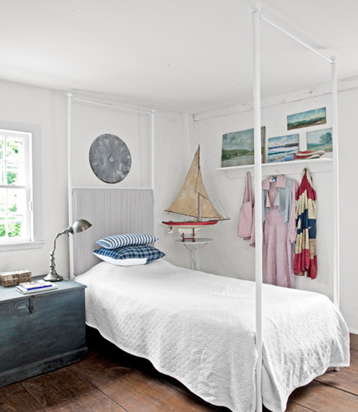 Inredning av ett shabby chic-inspirerat sovrum, med vita väggar, ljust trägolv och en spiselkrans i trä