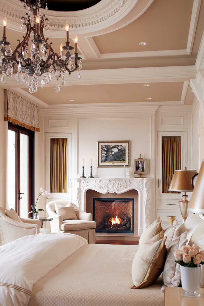 Imagen de dormitorio principal tradicional con paredes blancas, suelo de madera en tonos medios, todas las chimeneas y marco de chimenea de piedra