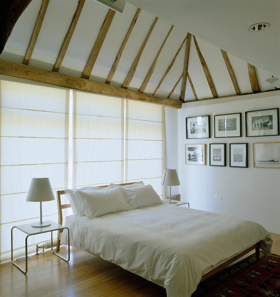 На фото: большая гостевая спальня (комната для гостей) на мансарде в стиле кантри с белыми стенами и паркетным полом среднего тона с