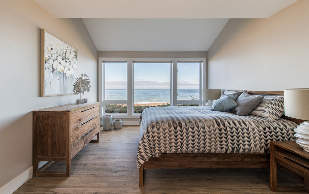 Ejemplo de habitación de invitados costera de tamaño medio con paredes beige, suelo de baldosas de porcelana y suelo marrón