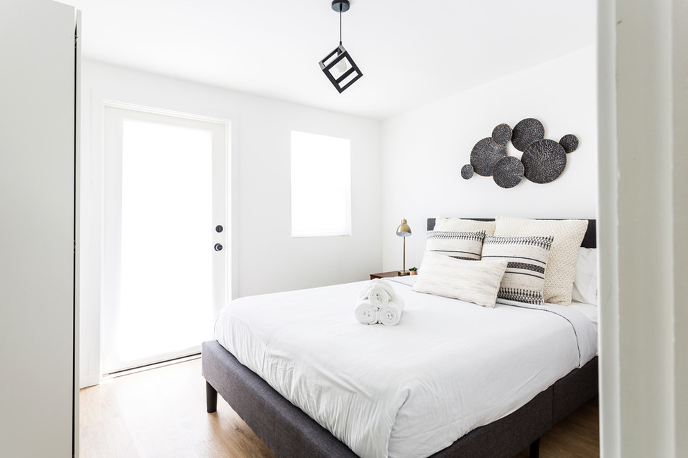 Diseño de dormitorio retro sin chimenea con paredes blancas y suelo de madera clara