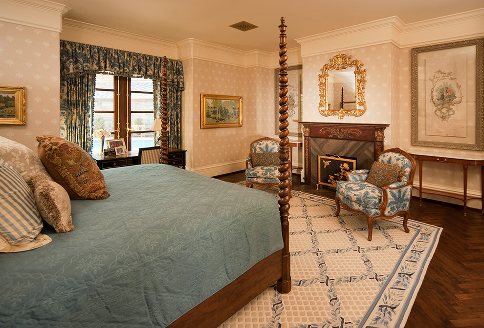 Großes Mediterranes Hauptschlafzimmer mit beiger Wandfarbe, dunklem Holzboden, Kamin und Kaminumrandung aus Holz in Houston