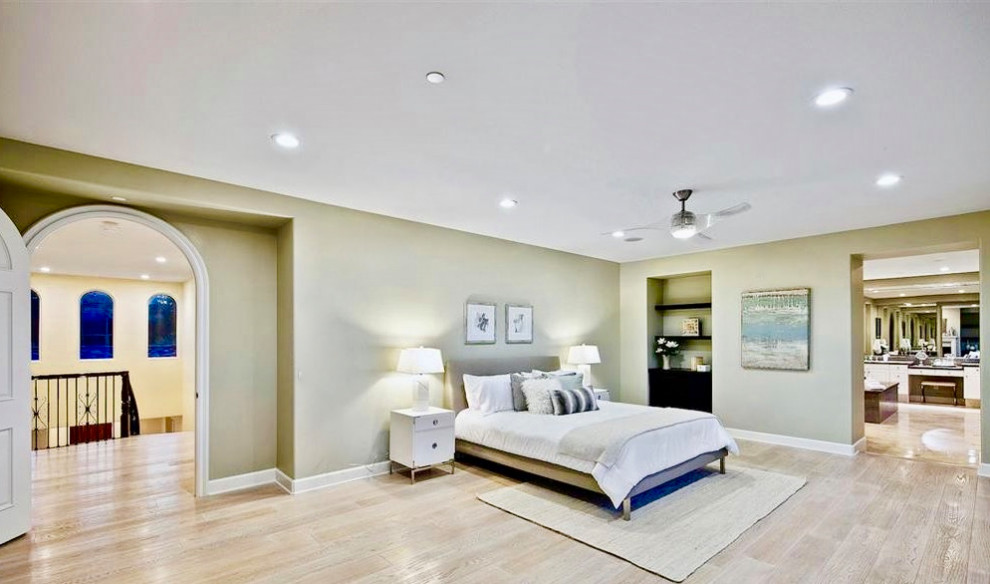 Geräumiges Mediterranes Hauptschlafzimmer mit grüner Wandfarbe, hellem Holzboden, Kamin, verputzter Kaminumrandung und grauem Boden in San Diego