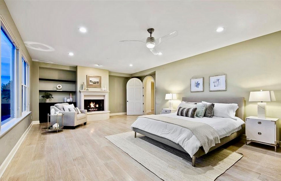 サンディエゴにある巨大な地中海スタイルのおしゃれな主寝室 (緑の壁、淡色無垢フローリング、標準型暖炉、漆喰の暖炉まわり、グレーの床) のレイアウト