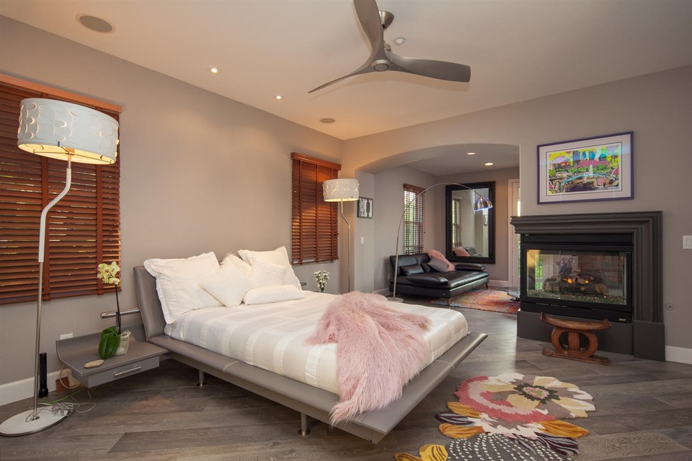 サンディエゴにある広い地中海スタイルのおしゃれな主寝室 (グレーの壁、セラミックタイルの床、コーナー設置型暖炉、コンクリートの暖炉まわり、茶色い床) のインテリア