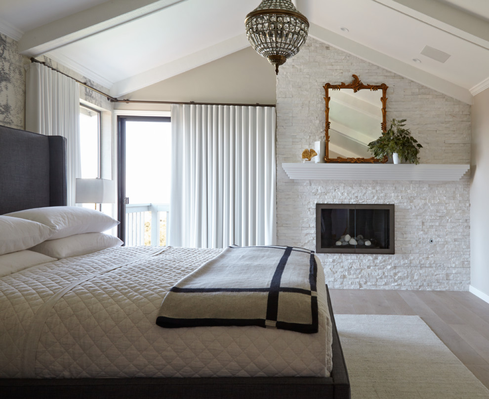Diseño de dormitorio principal tradicional renovado grande con paredes beige, suelo de madera clara, todas las chimeneas y marco de chimenea de piedra