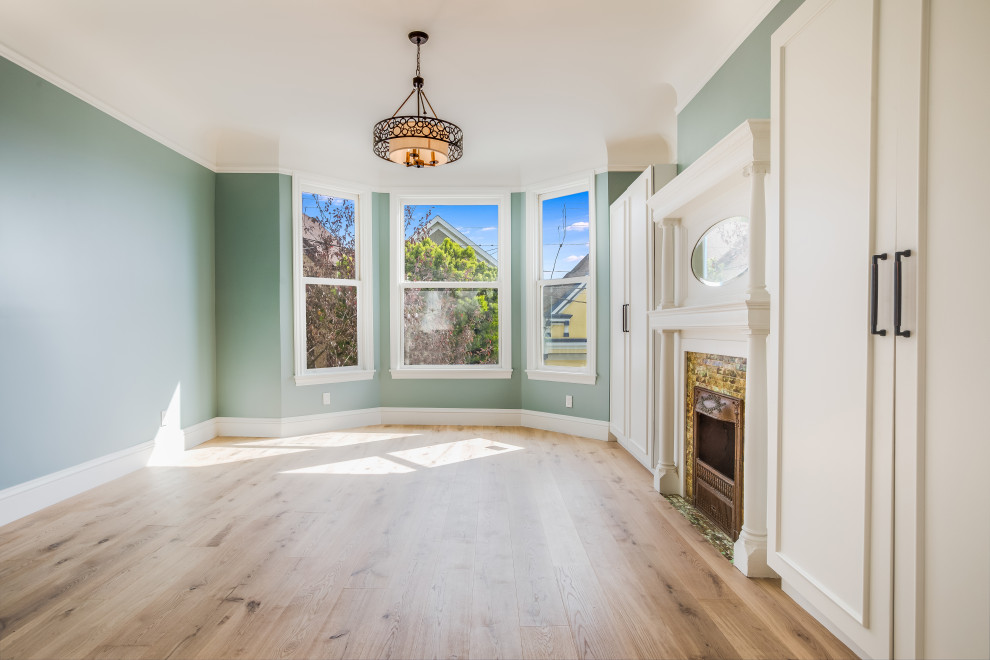 Klassisches Hauptschlafzimmer mit grüner Wandfarbe, hellem Holzboden, Kamin, gefliester Kaminumrandung und gewölbter Decke in San Francisco