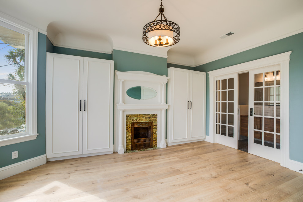 This is an example of a classic master bedroom in San Francisco with green walls, light hardwood flooring, a standard fireplace, a tiled fireplace surround and a vaulted ceiling.