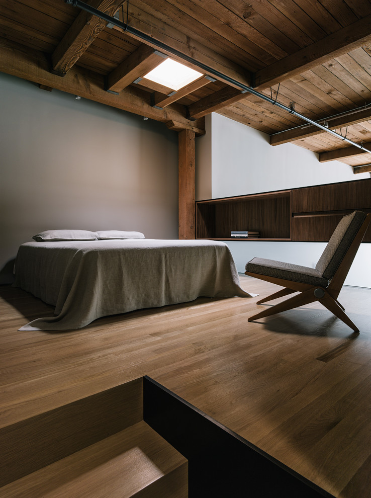 Ispirazione per una camera da letto stile loft industriale con pareti beige e pavimento in legno massello medio