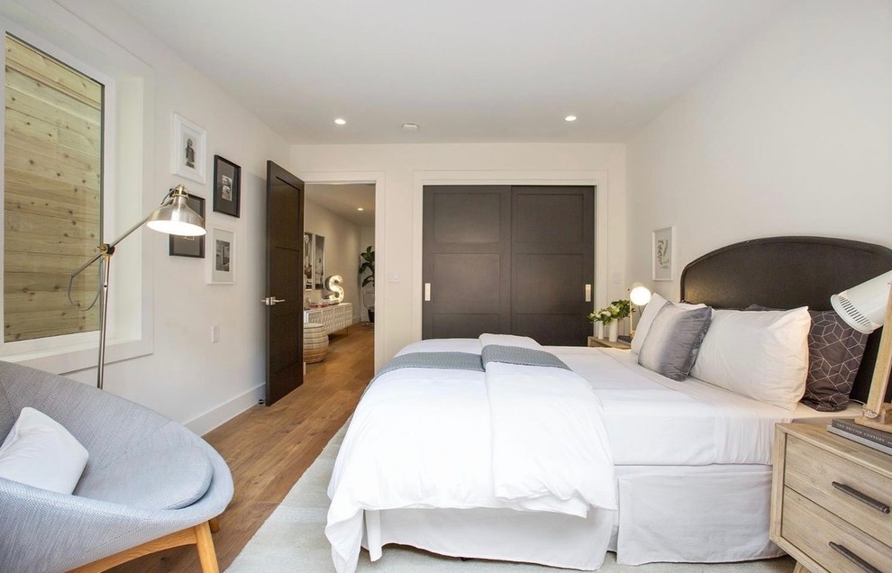 Foto di una camera degli ospiti design di medie dimensioni con pareti bianche, parquet chiaro, nessun camino e pavimento beige