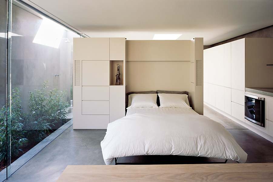 На фото: маленькая гостевая спальня (комната для гостей) в современном стиле с белыми стенами, бетонным полом и серым полом без камина для на участке и в саду