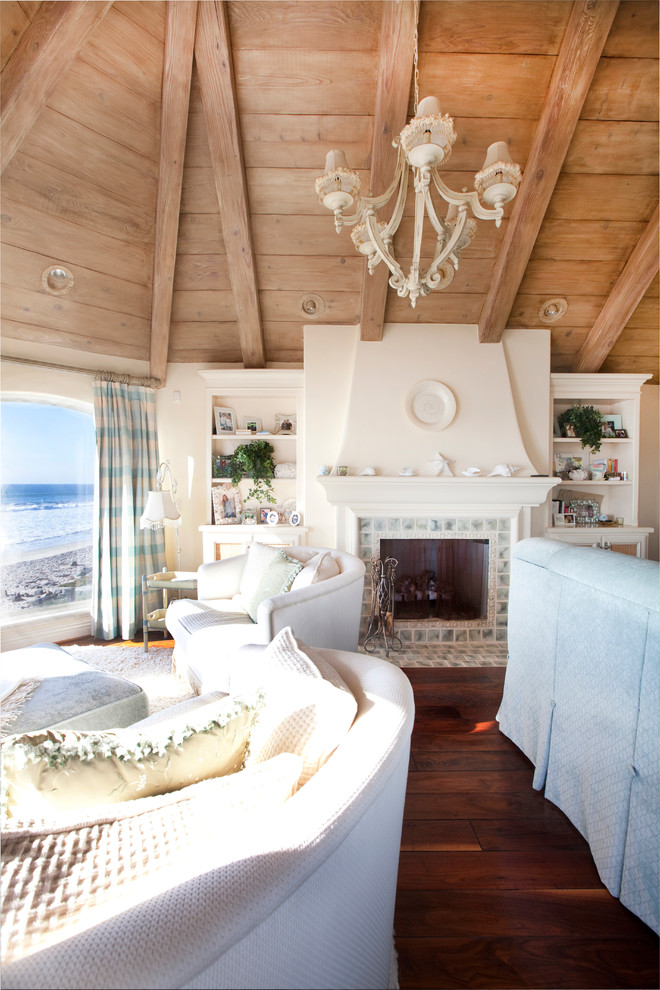 Exemple d'une grande chambre parentale méditerranéenne avec un mur beige, un sol en bois brun, une cheminée standard et un manteau de cheminée en carrelage.
