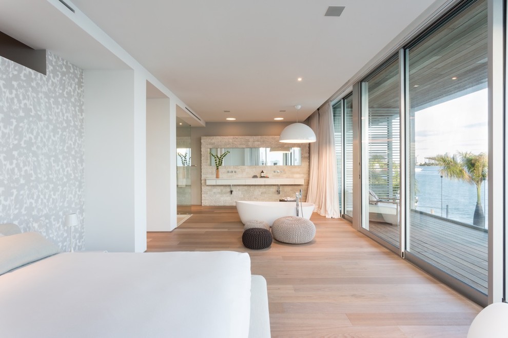 Diseño de dormitorio principal moderno grande sin chimenea con paredes blancas y suelo de madera clara