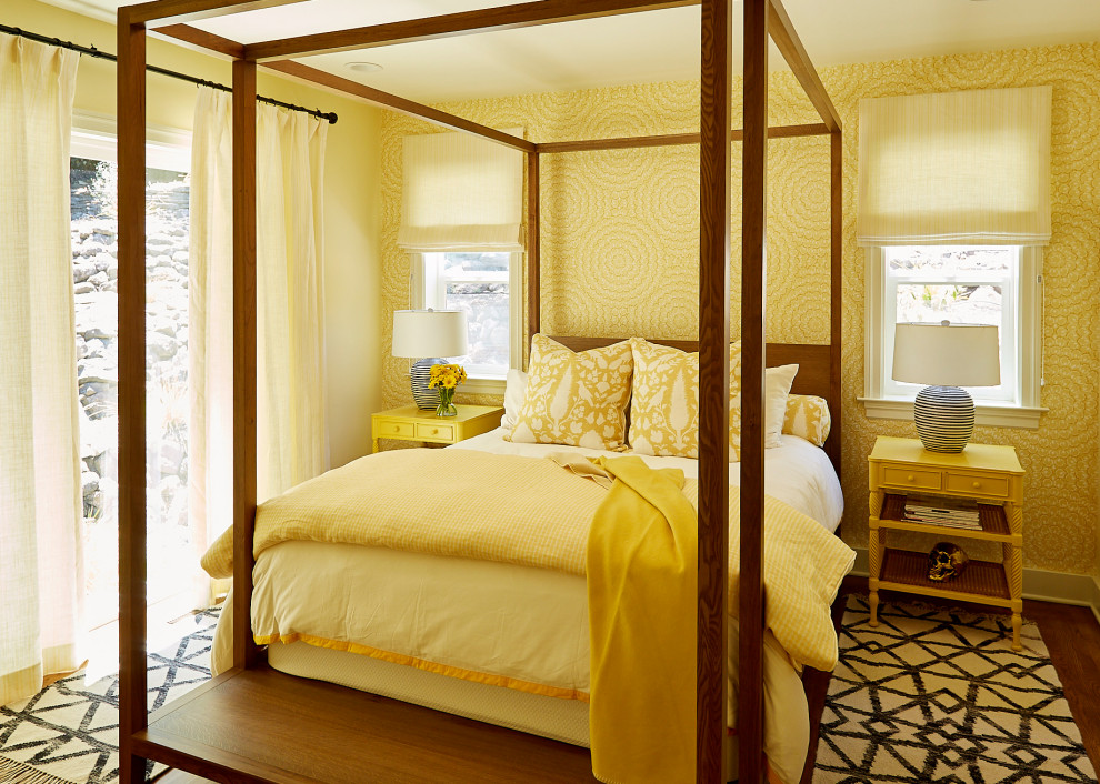 Modelo de dormitorio principal ecléctico de tamaño medio sin chimenea con paredes amarillas, suelo de madera en tonos medios, suelo marrón y papel pintado