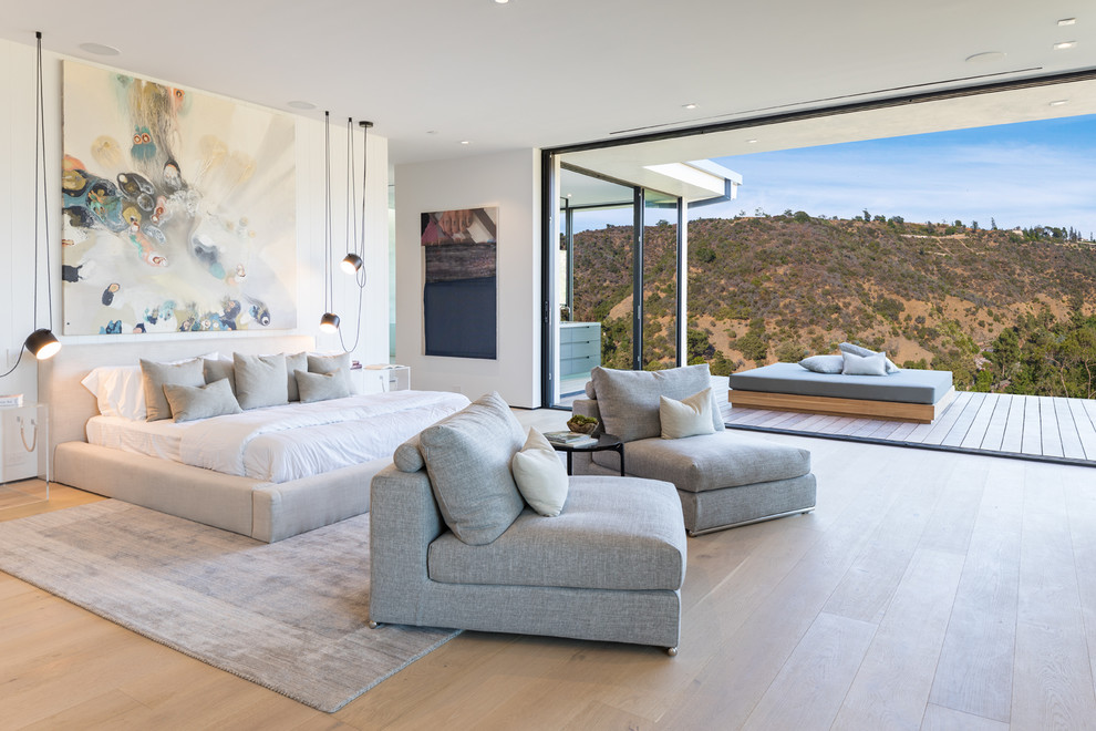 This is an example of a contemporary master bedroom in Los Angeles with white walls and light hardwood flooring.