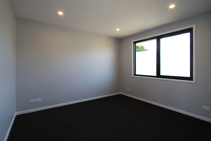 Imagen de habitación de invitados minimalista sin chimenea con paredes blancas, moqueta y suelo negro