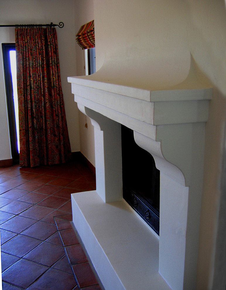 Réalisation d'une chambre parentale méditerranéenne de taille moyenne avec un mur blanc, tomettes au sol, une cheminée standard et un sol rouge.
