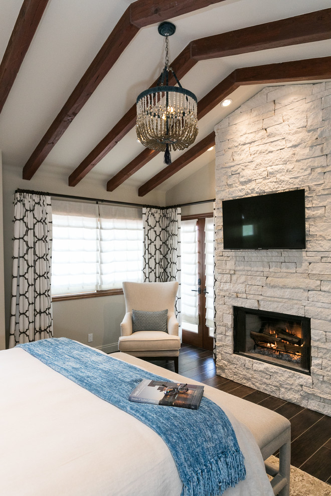 Mediterranes Hauptschlafzimmer mit weißer Wandfarbe, Kamin, Kaminumrandung aus Stein, braunem Boden und Porzellan-Bodenfliesen