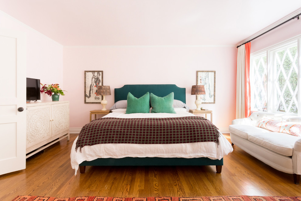 Large eclectic master bedroom in Los Angeles with pink walls, medium hardwood flooring, no fireplace and brown floors.