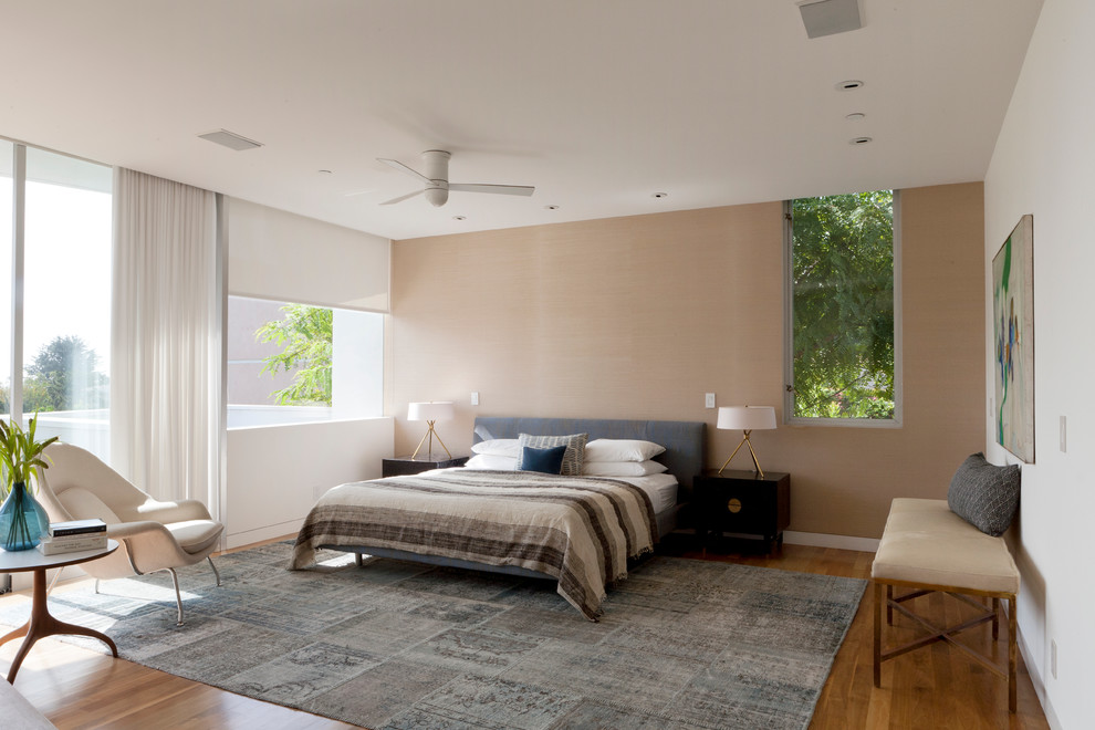 Modern bedroom in Los Angeles with medium hardwood flooring and a feature wall.