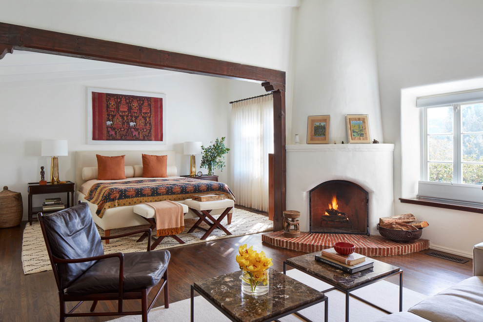ロサンゼルスにある地中海スタイルのおしゃれな主寝室 (白い壁、濃色無垢フローリング、コーナー設置型暖炉) のレイアウト