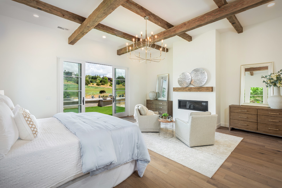 Inspiration for a farmhouse master bedroom in San Diego with white walls, medium hardwood flooring, a ribbon fireplace and brown floors.