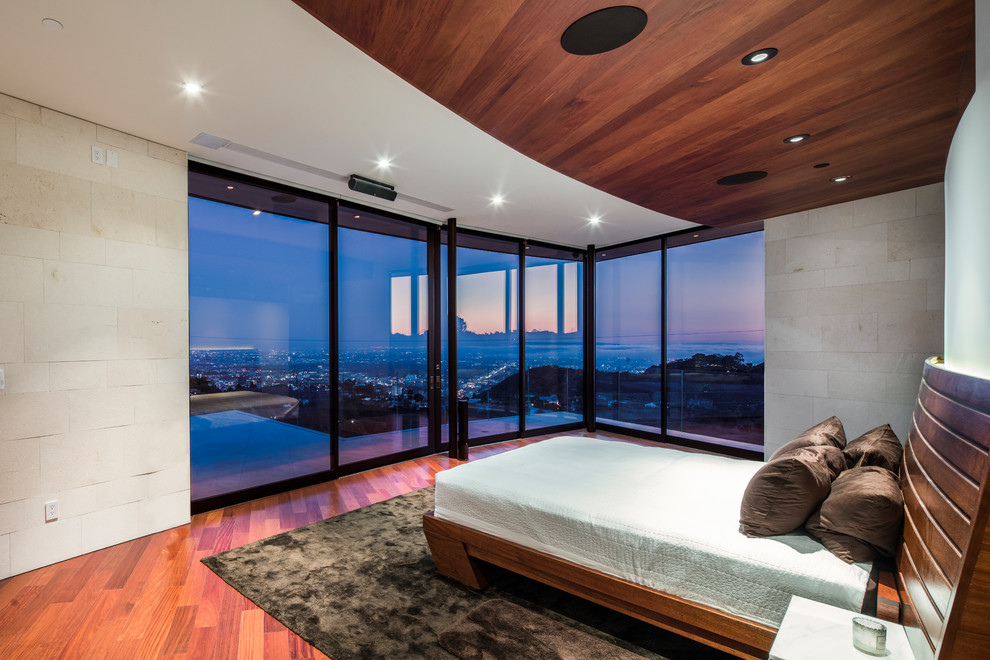 Diseño de dormitorio principal actual grande sin chimenea con paredes beige, suelo de madera en tonos medios y suelo rojo