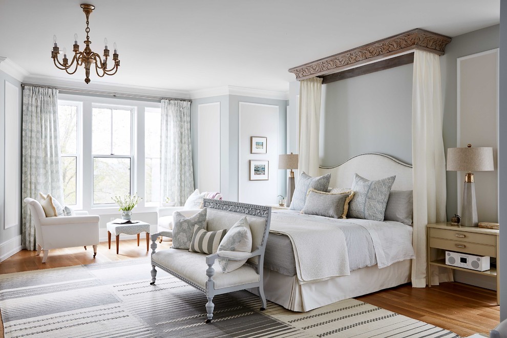 Immagine di una camera da letto country con pareti blu e pavimento in legno massello medio