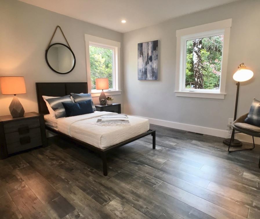 Idee per una camera degli ospiti minimal di medie dimensioni con pareti grigie, pavimento in legno massello medio e pavimento marrone