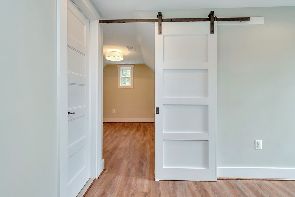 Cette photo montre une chambre parentale tendance de taille moyenne avec un sol en bois brun, aucune cheminée, un mur gris et un sol marron.