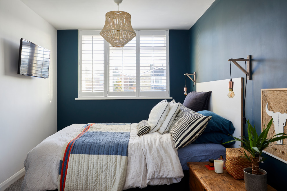 Photo of a contemporary bedroom in London with blue walls, carpet and grey floors.