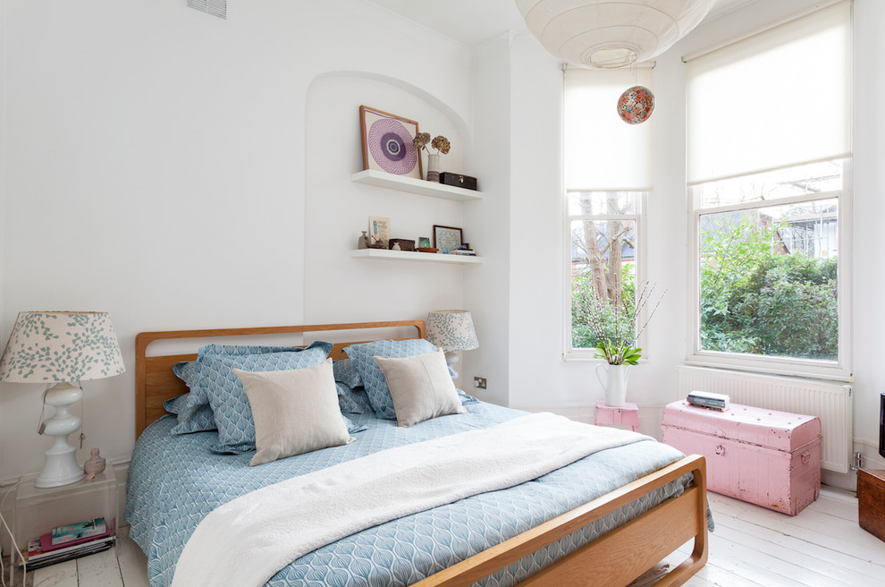 Nordisches Schlafzimmer ohne Kamin mit weißer Wandfarbe und gebeiztem Holzboden in London
