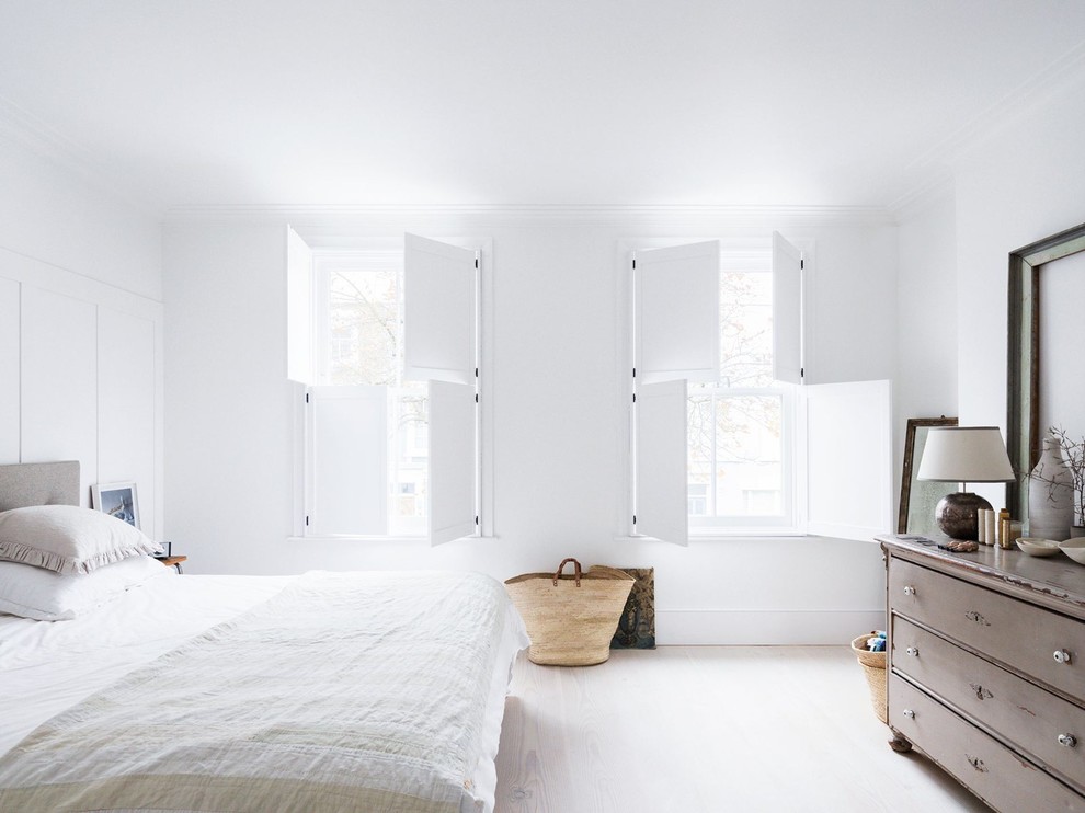 Medium sized scandi master bedroom in London with white walls, light hardwood flooring and no fireplace.