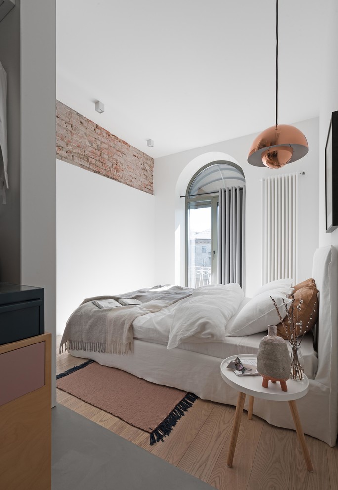 Skandinavisk inredning av ett sovrum, med vita väggar, ljust trägolv och beiget golv