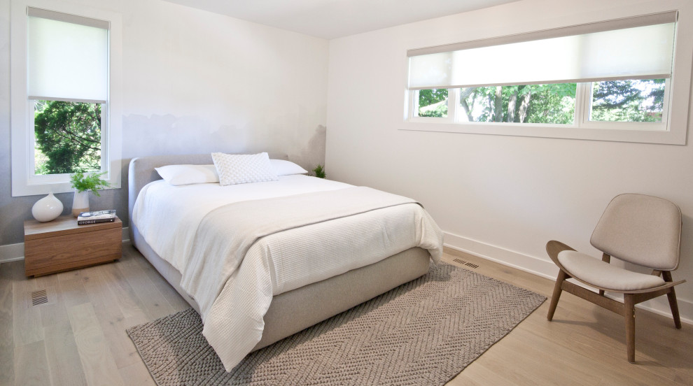 Inredning av ett modernt sovrum, med vita väggar, ljust trägolv och beiget golv